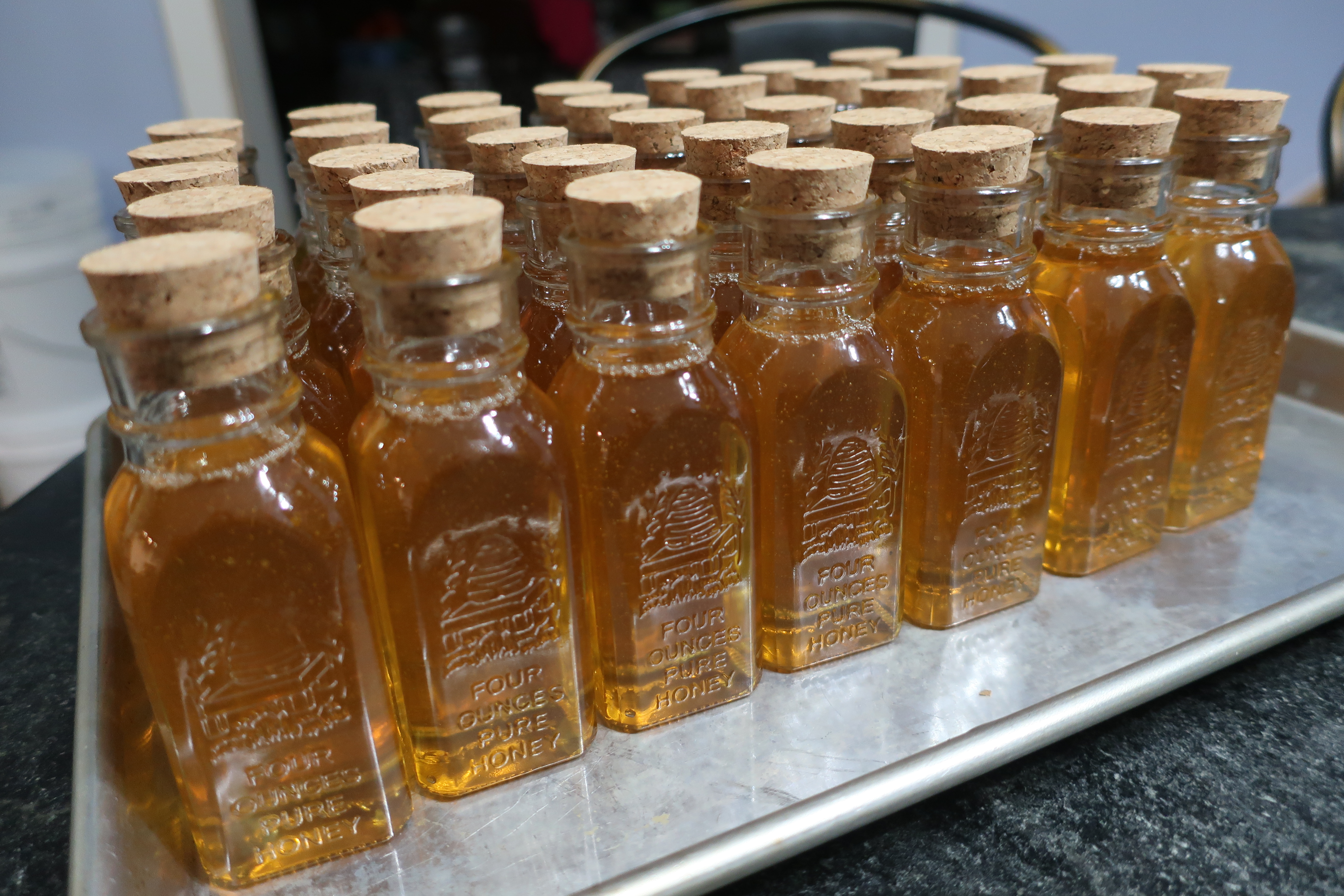 A tray of filled honey bottles closed with cork stoppers